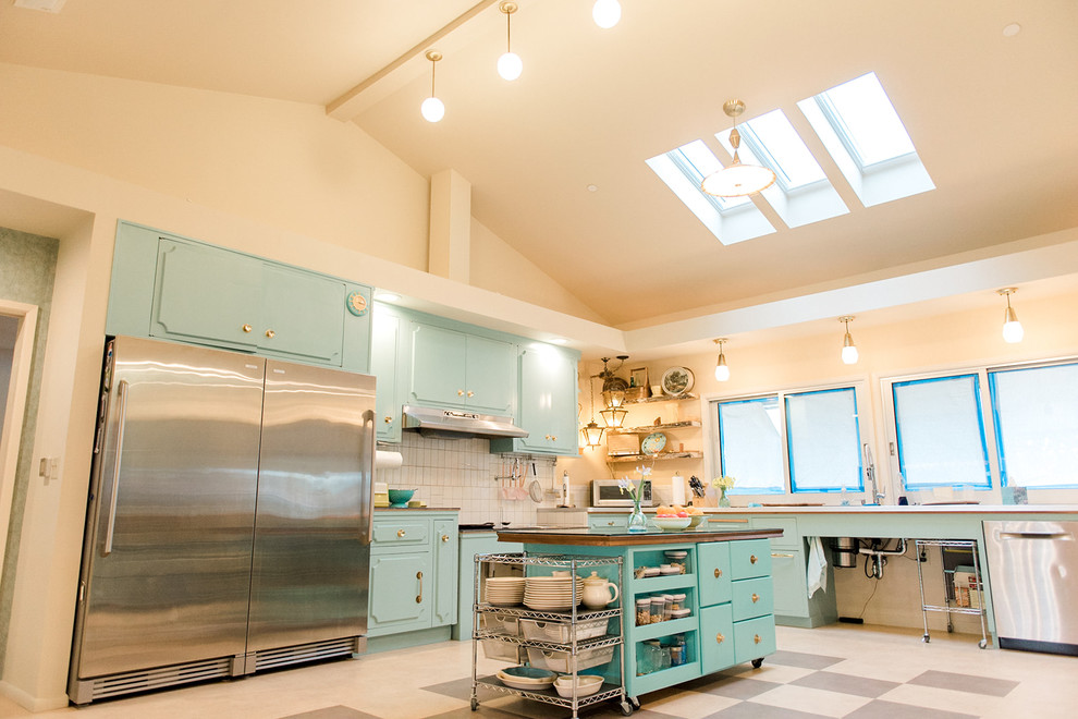 This is an example of a transitional l-shaped eat-in kitchen in San Francisco with an undermount sink, turquoise cabinets, beige splashback, ceramic splashback, stainless steel appliances, porcelain floors, with island, multi-coloured floor and white benchtop.