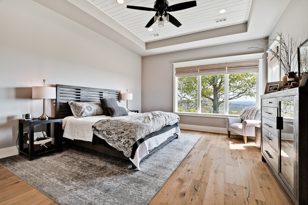 На фото: большая хозяйская спальня в стиле кантри с серыми стенами, светлым паркетным полом, многоуровневым потолком и стенами из вагонки с