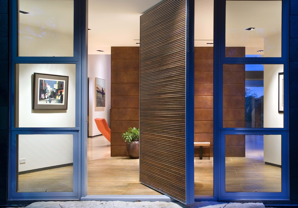 Modern entryway in Austin with a pivot front door and a medium wood front door.
