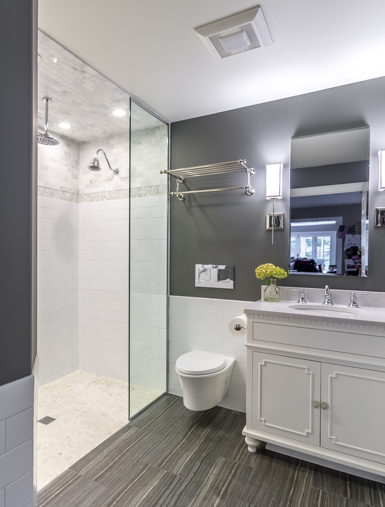 Photo of a small transitional 3/4 bathroom in Chicago with white cabinets, an open shower, a wall-mount toilet, white tile, subway tile, grey walls, ceramic floors, an undermount sink, marble benchtops, grey floor, an open shower, a single vanity, a freestanding vanity, white benchtops, wallpaper, decorative wall panelling and recessed-panel cabinets.