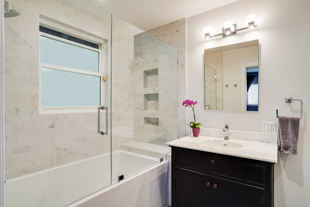 Design ideas for a mid-sized transitional master bathroom in San Francisco with furniture-like cabinets, black cabinets, an alcove tub, a shower/bathtub combo, a one-piece toilet, white tile, marble, white walls, porcelain floors, an undermount sink, marble benchtops, grey floor, a hinged shower door, white benchtops, a niche, a single vanity and a freestanding vanity.
