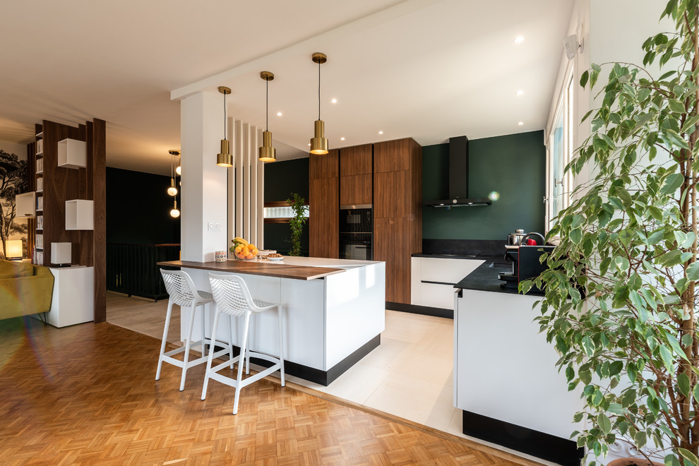 Photo of a mid-sized transitional l-shaped open plan kitchen in Lyon with an undermount sink, solid surface benchtops, black splashback, stainless steel appliances, ceramic floors, with island, beige floor and black benchtop.