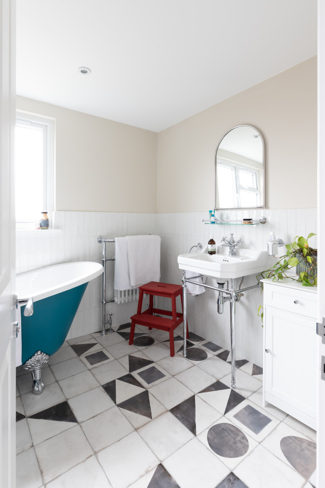 Стильный дизайн: ванная комната среднего размера в классическом стиле с фасадами в стиле шейкер, белыми фасадами, отдельно стоящей ванной, угловым душем, унитазом-моноблоком, белой плиткой, керамогранитной плиткой, полом из керамогранита, подвесной раковиной, разноцветным полом, душем с раздвижными дверями, белой столешницей, акцентной стеной, белыми стенами, тумбой под одну раковину и напольной тумбой - последний тренд