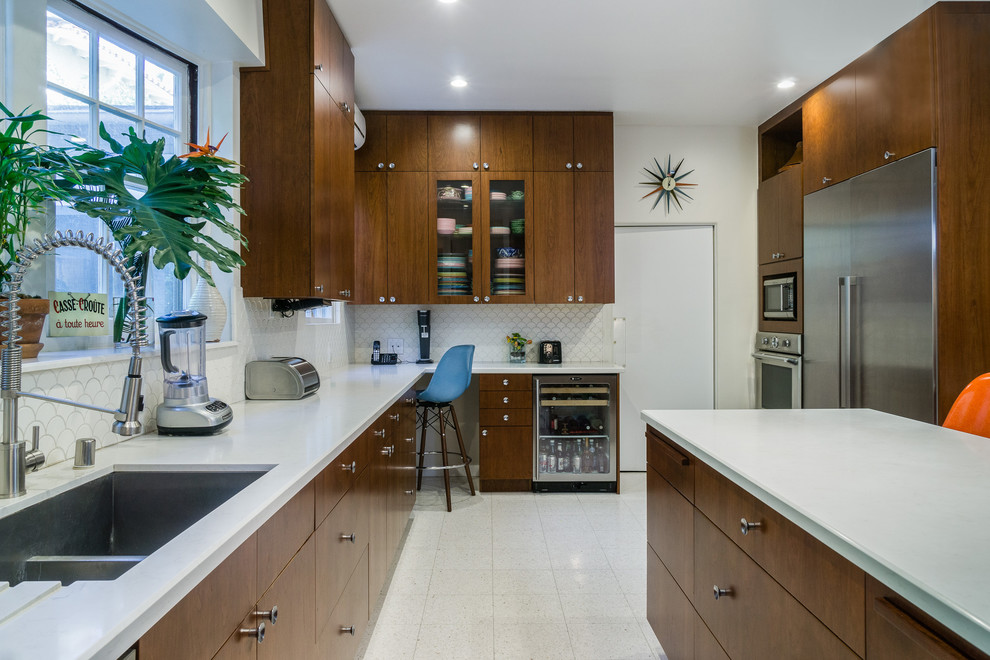 Large midcentury galley separate kitchen in Los Angeles with a single-bowl sink, flat-panel cabinets, medium wood cabinets, quartz benchtops, white splashback, ceramic splashback, stainless steel appliances, linoleum floors, with island and white floor.