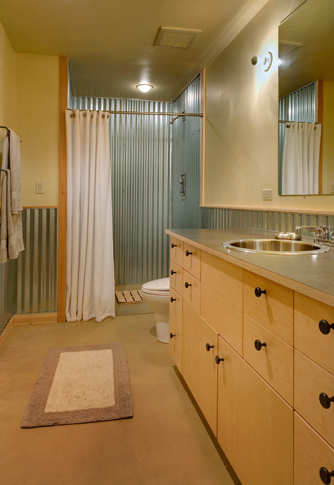 Design ideas for a mid-sized contemporary 3/4 bathroom in Seattle with flat-panel cabinets, light wood cabinets, an alcove shower, a one-piece toilet, gray tile, metal tile, beige walls, concrete floors, a drop-in sink and laminate benchtops.