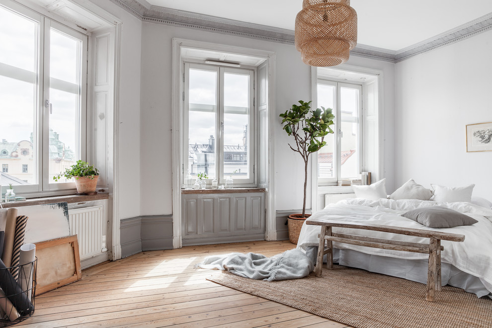 Large scandinavian master bedroom in Stockholm with white walls and light hardwood floors.