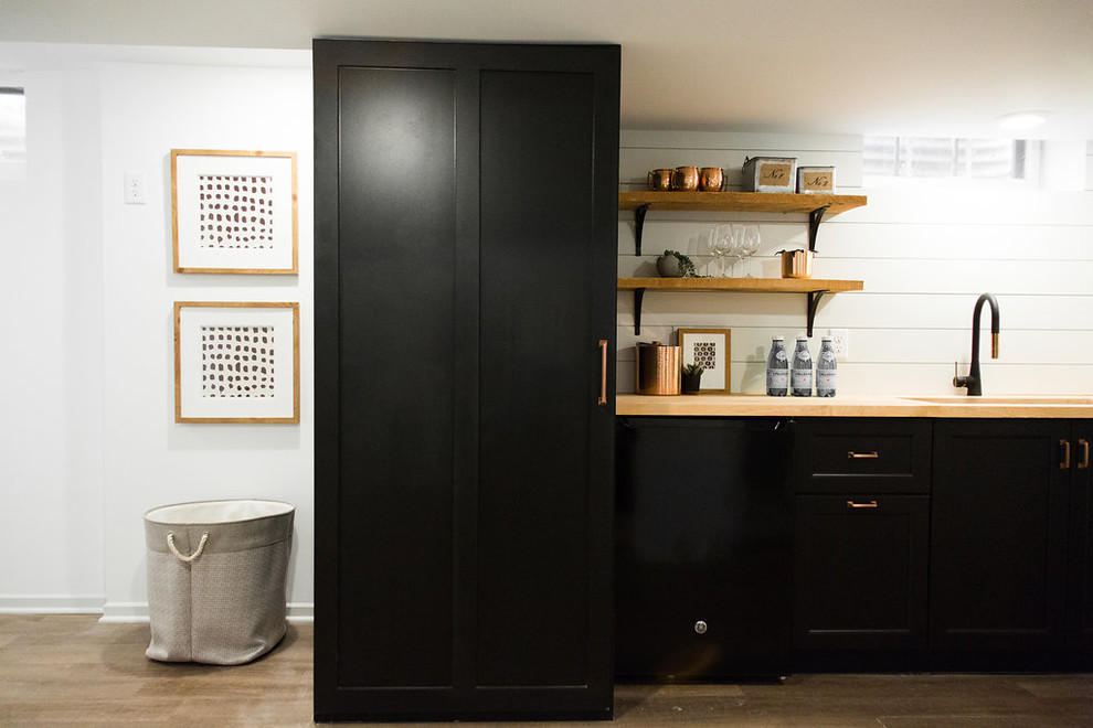 This is an example of a mid-sized transitional single-wall wet bar in Minneapolis with an undermount sink, shaker cabinets, black cabinets, wood benchtops, white splashback, timber splashback, vinyl floors, brown floor and beige benchtop.