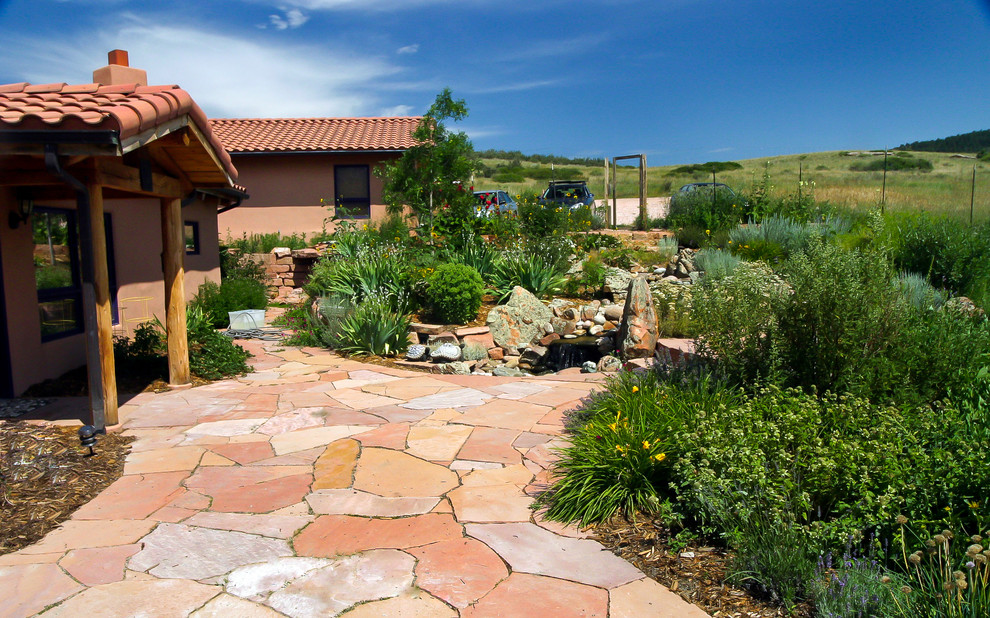 This is an example of a large country courtyard patio in Denver with a vegetable garden, natural stone pavers and a roof extension.