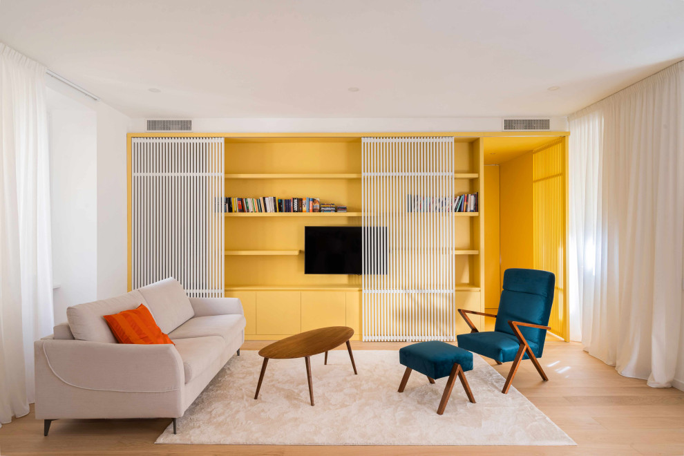 Cette image montre un petit salon design ouvert avec une bibliothèque ou un coin lecture, un mur jaune, parquet clair, un téléviseur dissimulé, un sol beige et boiseries.