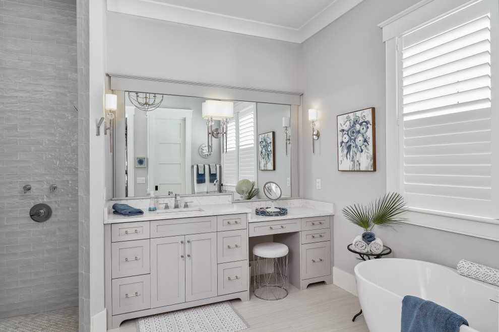 Inspiration for a mid-sized beach style master bathroom in Charleston with grey cabinets, a freestanding tub, grey walls, an undermount sink, white benchtops, a single vanity, a built-in vanity, an open shower, grey floor and an open shower.