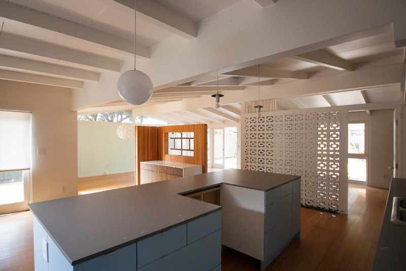 Mid-sized midcentury single-wall open plan kitchen in Orange County with flat-panel cabinets, white cabinets, grey splashback and with island.
