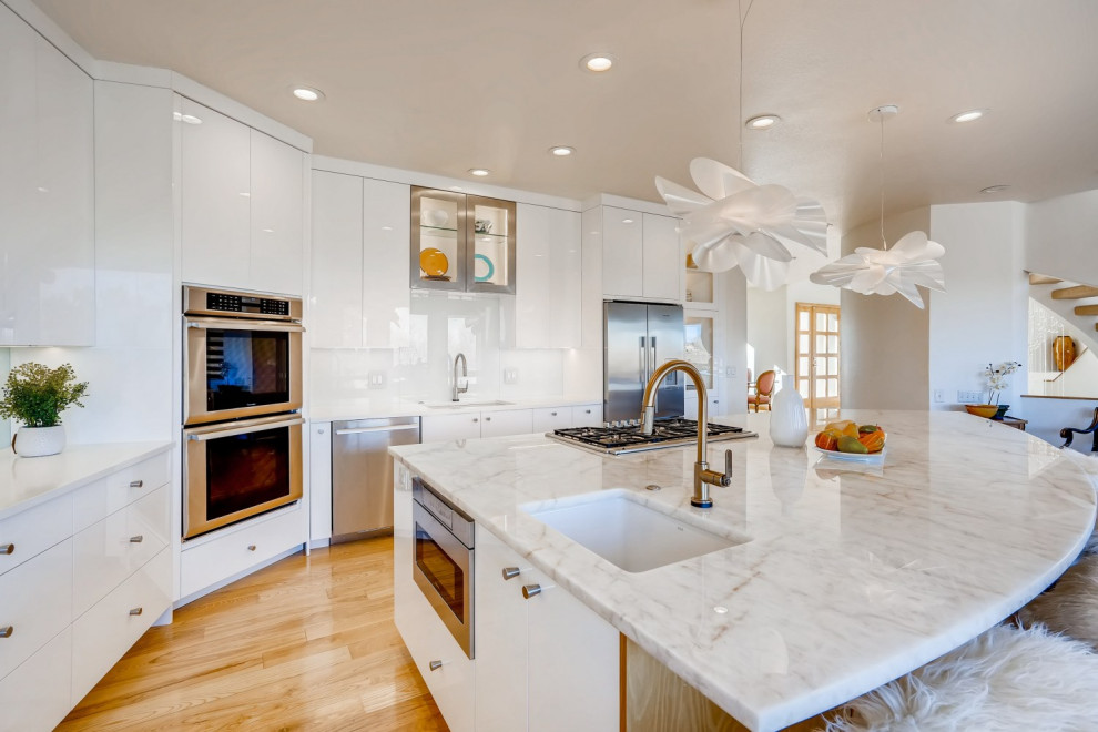 Photo of a large contemporary l-shaped open plan kitchen in Denver with a single-bowl sink, flat-panel cabinets, white cabinets, quartzite benchtops, green splashback, glass sheet splashback, stainless steel appliances, light hardwood floors, with island, yellow floor and white benchtop.