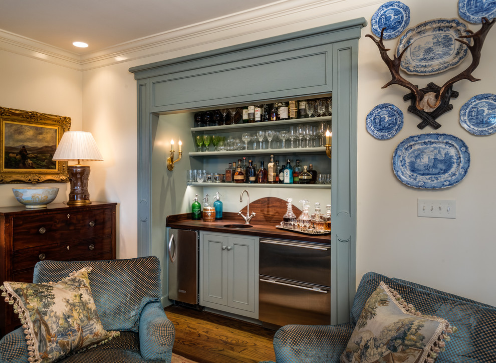 Inspiration for a mid-sized traditional single-wall wet bar in Birmingham with brown floor, an undermount sink, recessed-panel cabinets, blue cabinets, wood benchtops, dark hardwood floors and brown benchtop.