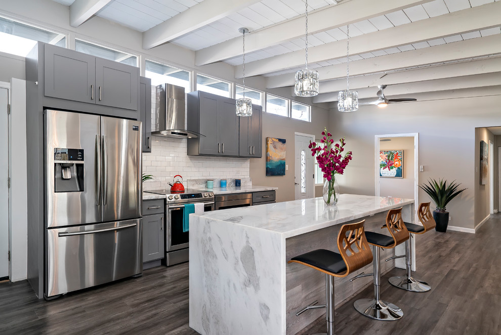 Kitchen - transitional single-wall dark wood floor and gray floor kitchen idea in Hawaii with shaker cabinets, gray cabinets, white backsplash, subway tile backsplash, stainless steel appliances, an island and white countertops