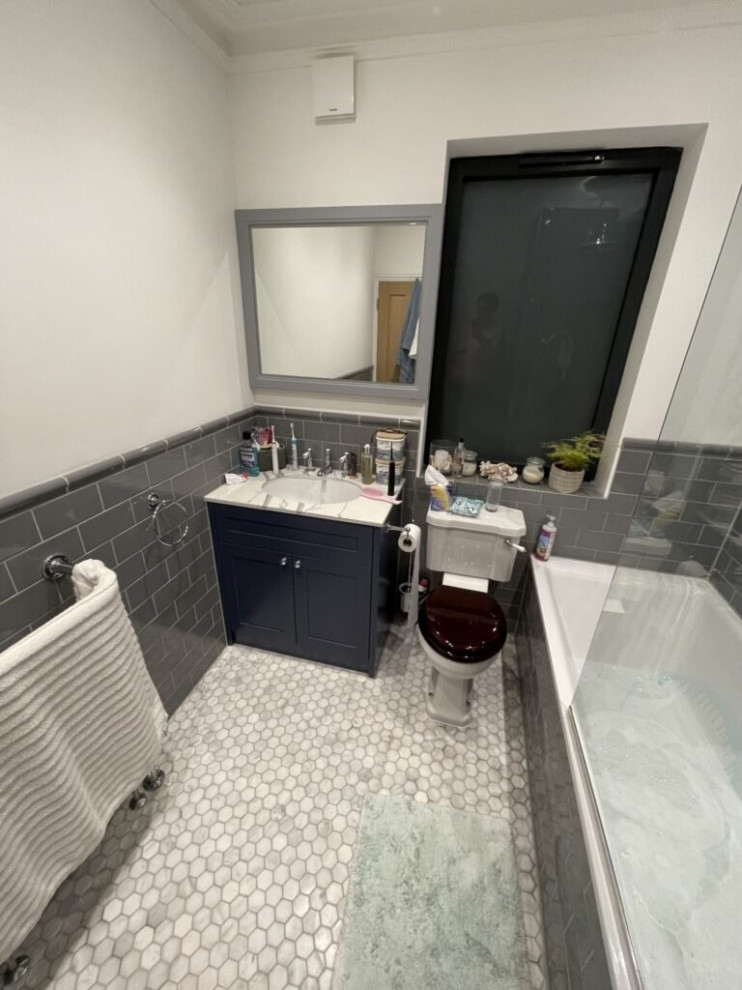 Photo of a small contemporary kids bathroom in London with open cabinets, black cabinets, a drop-in tub, a shower/bathtub combo, a one-piece toilet, gray tile, ceramic tile, green walls, brick floors, a drop-in sink, stainless steel benchtops, grey floor, a sliding shower screen, white benchtops, a single vanity, a built-in vanity and wood.