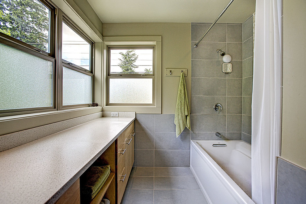 Contemporary bathroom in Seattle with an undermount sink, flat-panel cabinets, light wood cabinets, engineered quartz benchtops, an alcove tub, a shower/bathtub combo, a two-piece toilet, gray tile, ceramic tile, green walls and ceramic floors.