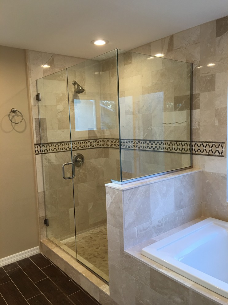 Inspiration for a mid-sized transitional master bathroom in Tampa with a drop-in tub, an alcove shower, beige tile, travertine, beige walls, vinyl floors, brown floor and a hinged shower door.