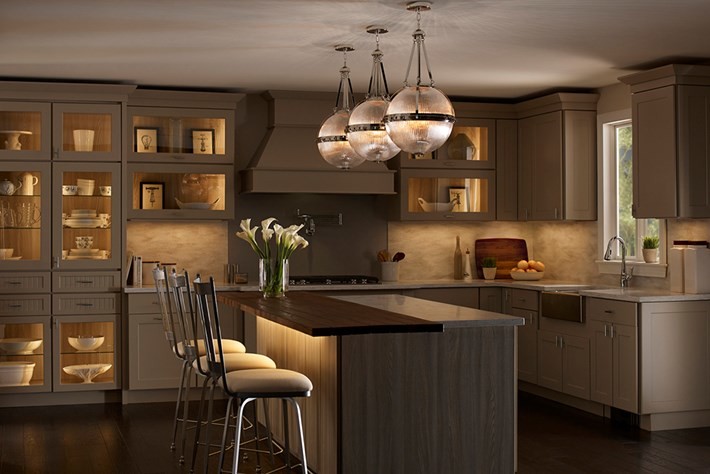 Transitional medium tone wood floor and brown floor kitchen photo with a farmhouse sink, glass-front cabinets, beige cabinets, granite countertops, multicolored backsplash, colored appliances and an island