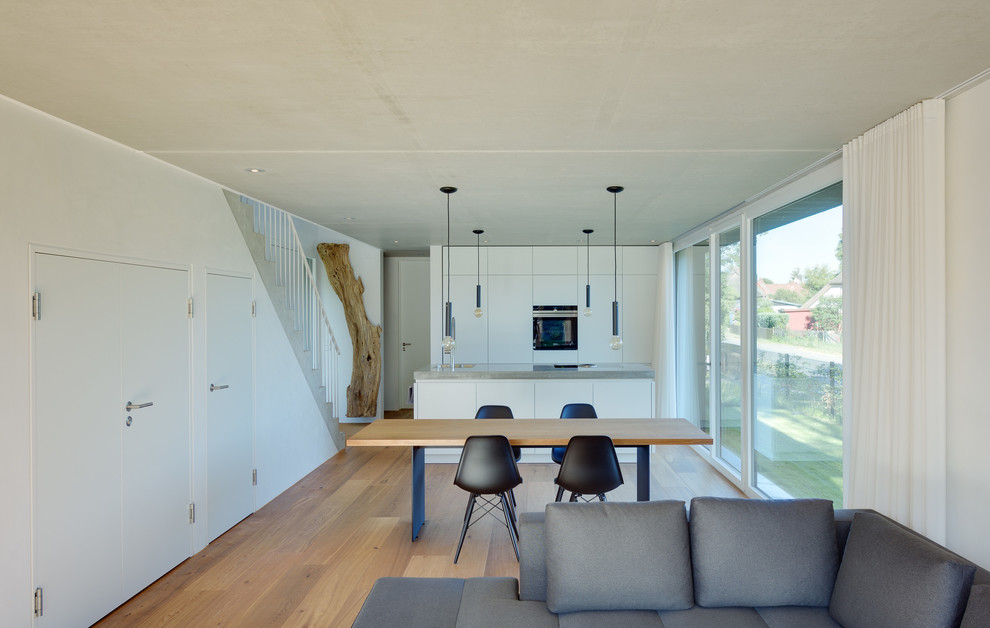This is an example of a mid-sized contemporary open concept family room in Berlin with white walls and medium hardwood floors.