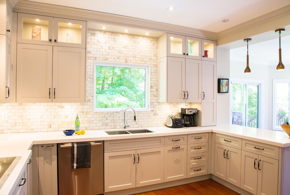 Inspiration for a mid-sized transitional u-shaped medium tone wood floor kitchen remodel with an undermount sink, white cabinets, quartzite countertops, white backsplash, subway tile backsplash, stainless steel appliances and a peninsula