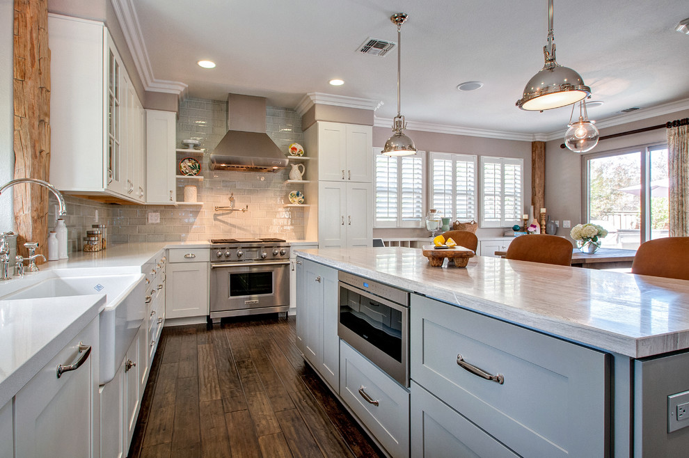 Eat-in kitchen - mid-sized transitional l-shaped dark wood floor eat-in kitchen idea in San Diego with a farmhouse sink, shaker cabinets, white cabinets, marble countertops, blue backsplash, ceramic backsplash, stainless steel appliances and an island