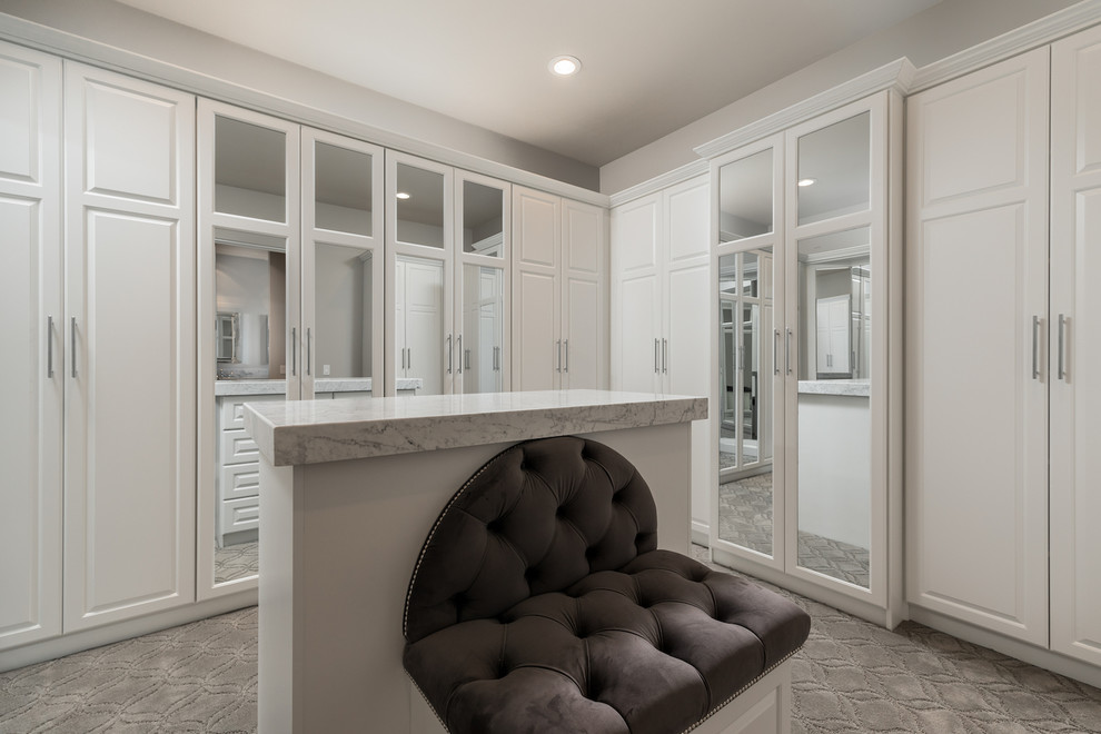 Design ideas for an expansive mediterranean gender-neutral dressing room in Phoenix with recessed-panel cabinets, white cabinets, carpet and grey floor.