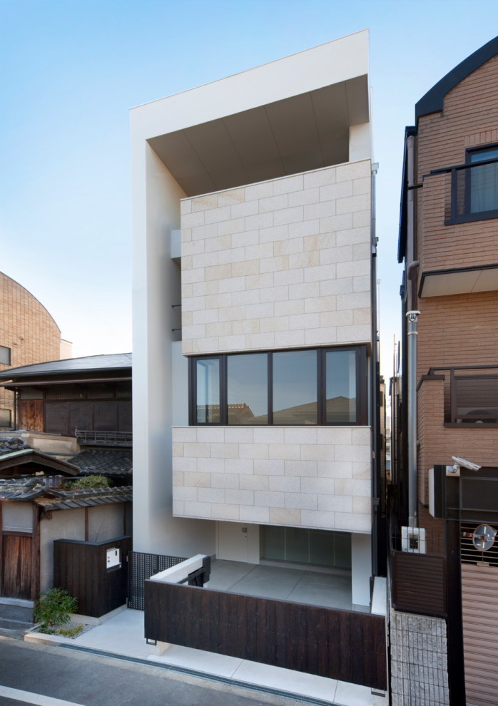 Inspiration for a large grey house exterior in Osaka with four or more storeys, stone veneer, a flat roof, a green roof and a white roof.