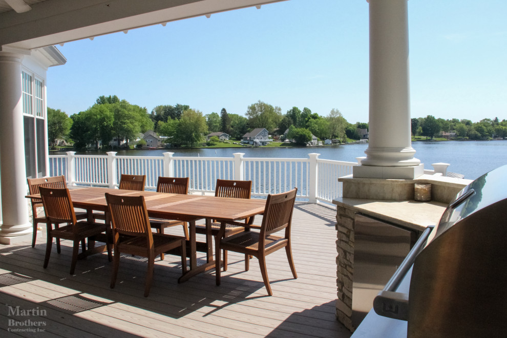 Huge beach style backyard outdoor kitchen deck photo in Grand Rapids with a roof extension