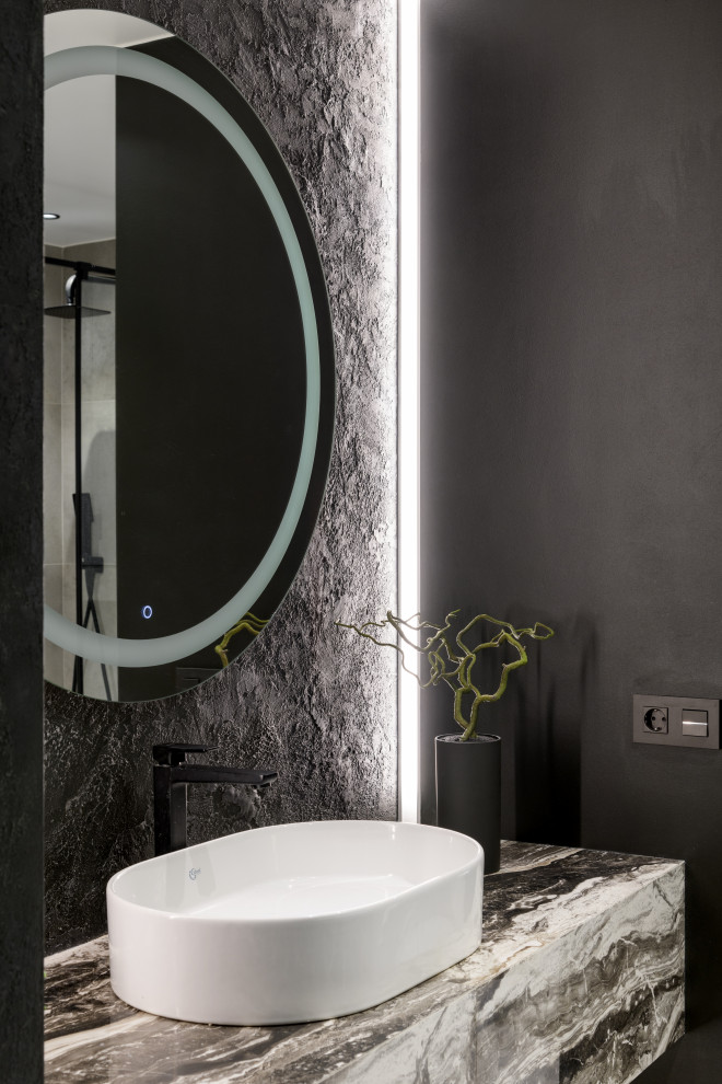 This is an example of a large contemporary 3/4 bathroom in Novosibirsk with flat-panel cabinets, grey cabinets, an undermount tub, an alcove shower, a wall-mount toilet, gray tile, porcelain tile, black walls, porcelain floors, a drop-in sink, tile benchtops, grey floor, a hinged shower door, grey benchtops, a single vanity and a floating vanity.