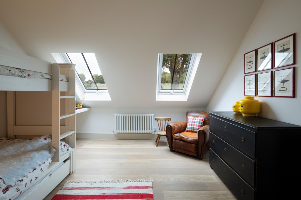This is an example of a large contemporary kids' room in Hampshire with white walls and light hardwood floors.