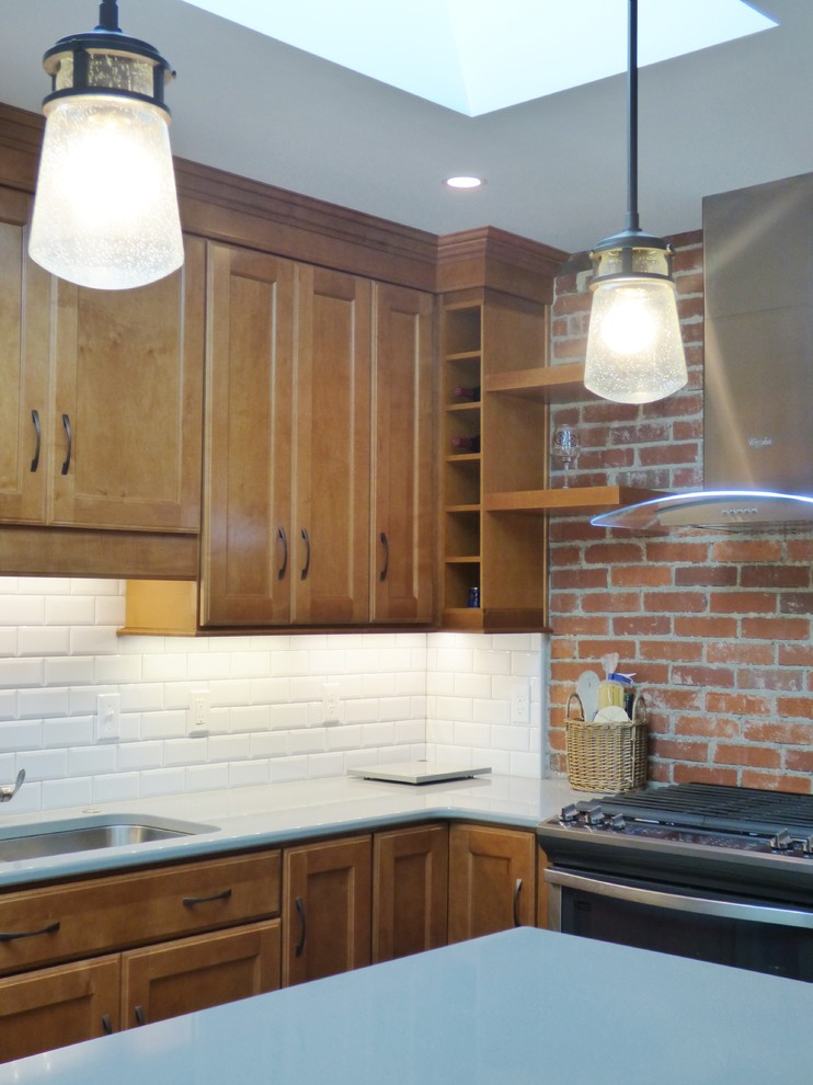 Example of a transitional l-shaped porcelain tile eat-in kitchen design with an undermount sink, recessed-panel cabinets, medium tone wood cabinets, quartz countertops, white backsplash, subway tile backsplash, stainless steel appliances and an island