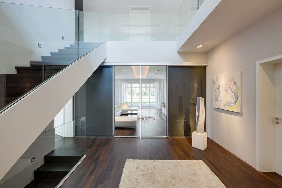 Expansive contemporary foyer in Berlin with grey walls and dark hardwood floors.