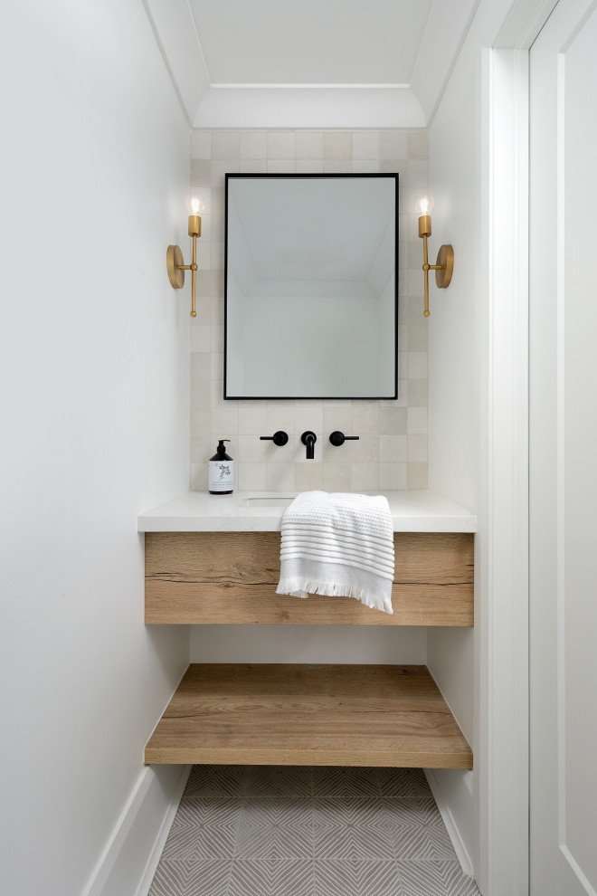 Идея дизайна: туалет в стиле модернизм с светлыми деревянными фасадами, белой плиткой, керамической плиткой, белыми стенами, полом из керамической плитки, накладной раковиной, столешницей из искусственного кварца, серым полом, белой столешницей и подвесной тумбой