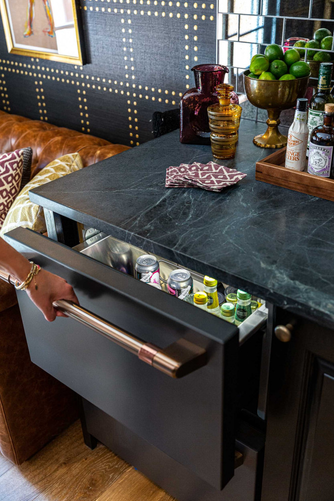 This is an example of a mid-sized eclectic home bar in San Francisco with black cabinets, soapstone benchtops, multi-coloured splashback, mirror splashback, light hardwood floors and multi-coloured benchtop.