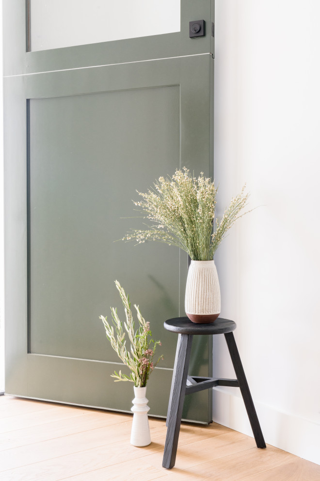 Design ideas for a mid-sized scandinavian front door in Orange County with white walls, light hardwood floors, a dutch front door, a green front door, brown floor and vaulted.