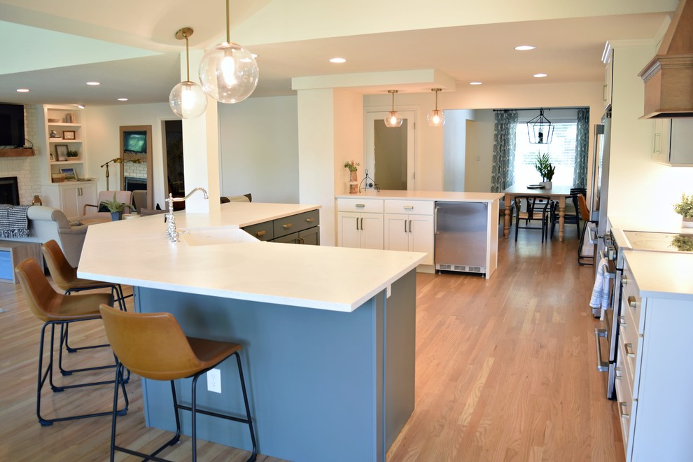 This is an example of an expansive traditional l-shaped open plan kitchen in Denver with a farmhouse sink, shaker cabinets, white cabinets, white splashback, subway tile splashback, stainless steel appliances and with island.