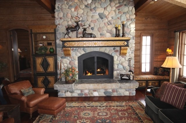 Design ideas for a mid-sized country living room in Denver with medium hardwood floors, a standard fireplace, a stone fireplace surround, brown walls, no tv and brown floor.