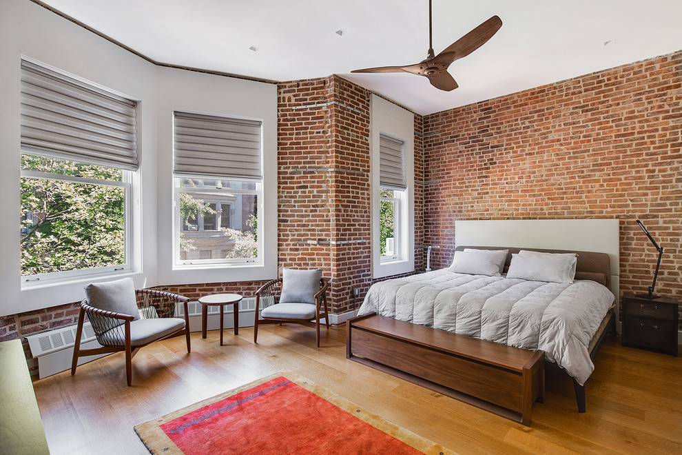 Design ideas for an industrial master bedroom in New York with red walls and medium hardwood floors.