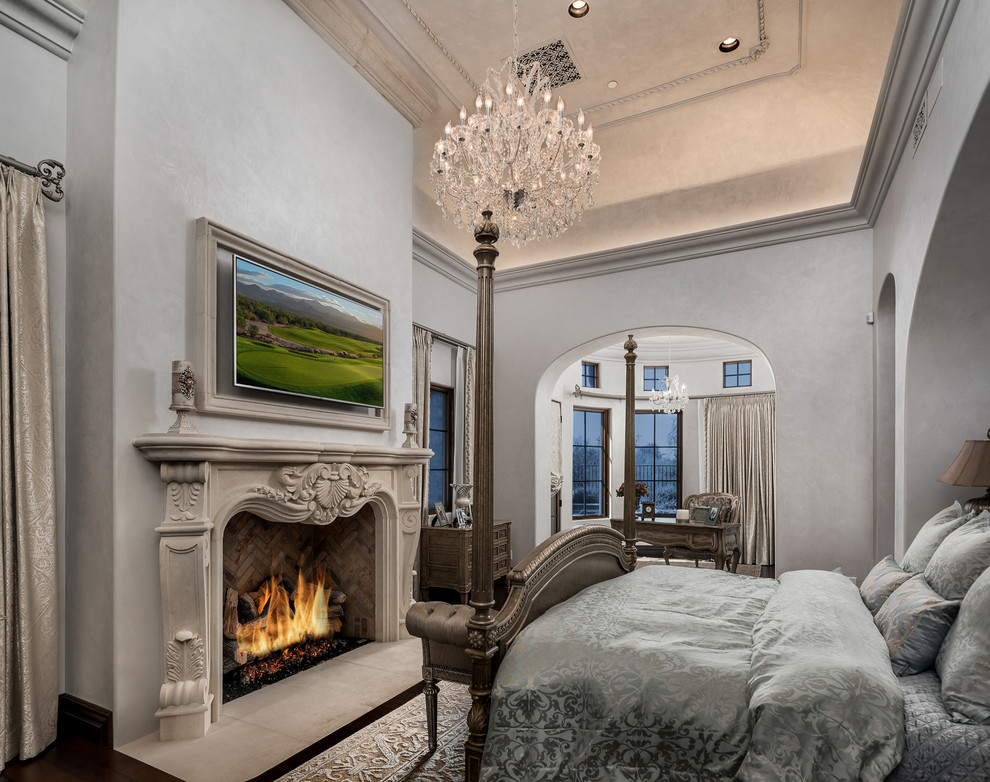 Inspiration for an expansive traditional master bedroom in Phoenix with grey walls, medium hardwood floors, a standard fireplace, a stone fireplace surround and brown floor.