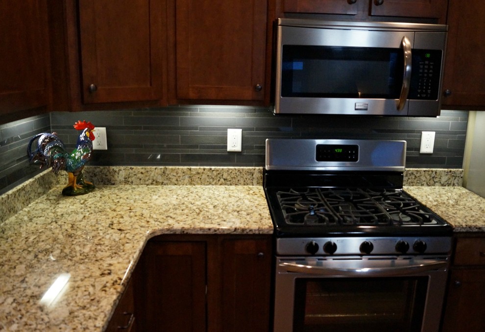 Example of a mid-sized transitional u-shaped open concept kitchen design in Cedar Rapids with shaker cabinets, dark wood cabinets, granite countertops, black backsplash, porcelain backsplash, stainless steel appliances and an island