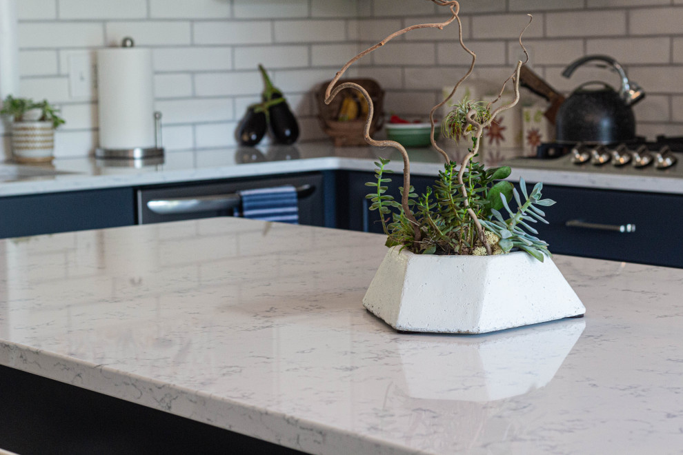 Example of a mid-sized transitional l-shaped porcelain tile and gray floor eat-in kitchen design with an undermount sink, flat-panel cabinets, white cabinets, quartz countertops, white backsplash, subway tile backsplash, stainless steel appliances, an island and white countertops