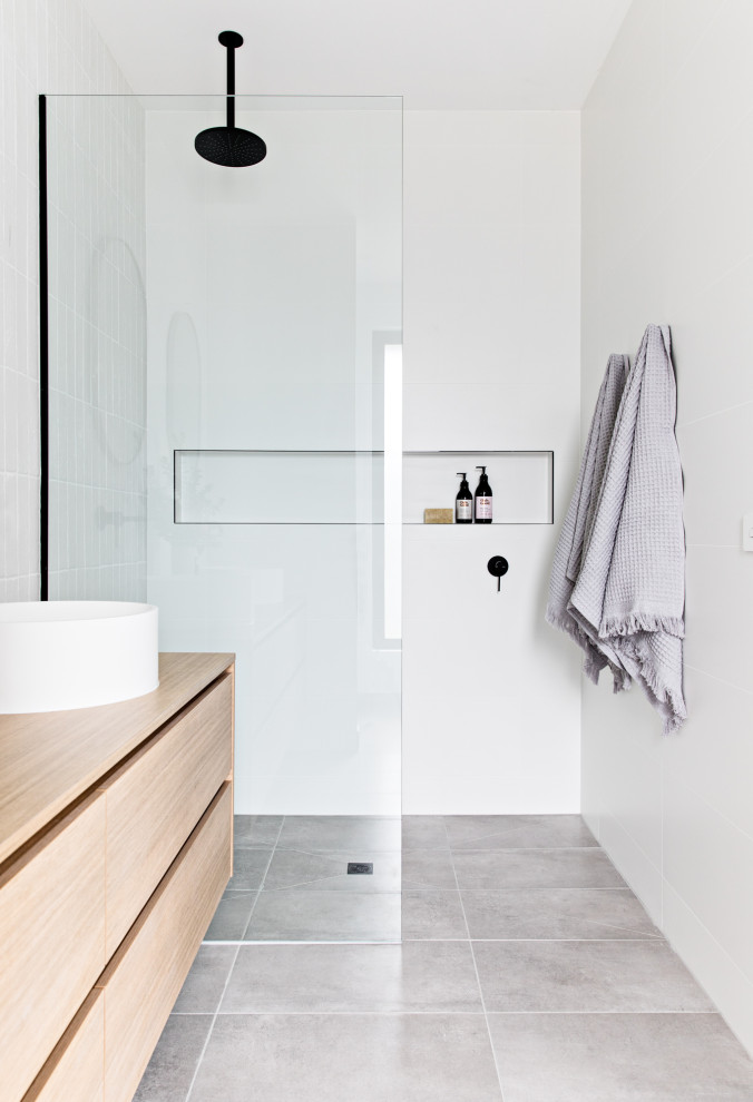 Photo of a scandinavian bathroom in Melbourne with flat-panel cabinets, light wood cabinets, a curbless shower, gray tile, a vessel sink, wood benchtops, grey floor, an open shower and beige benchtops.