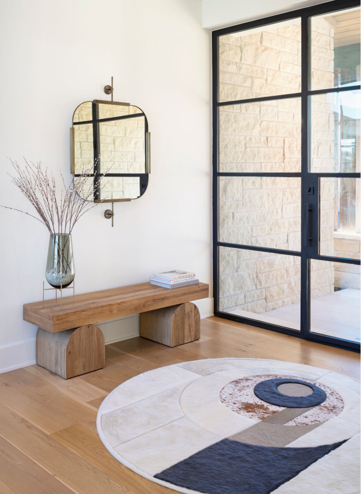 Ispirazione per un ingresso minimal con pareti bianche, pavimento in legno massello medio, una porta singola, una porta in vetro e pavimento marrone