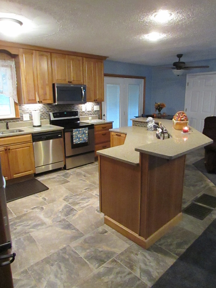 Home design - mid-sized transitional l-shaped ceramic tile home design idea with a double-bowl sink, raised-panel cabinets, light wood cabinets, quartz countertops, multicolored backsplash, mosaic tile backsplash, stainless steel appliances and an island