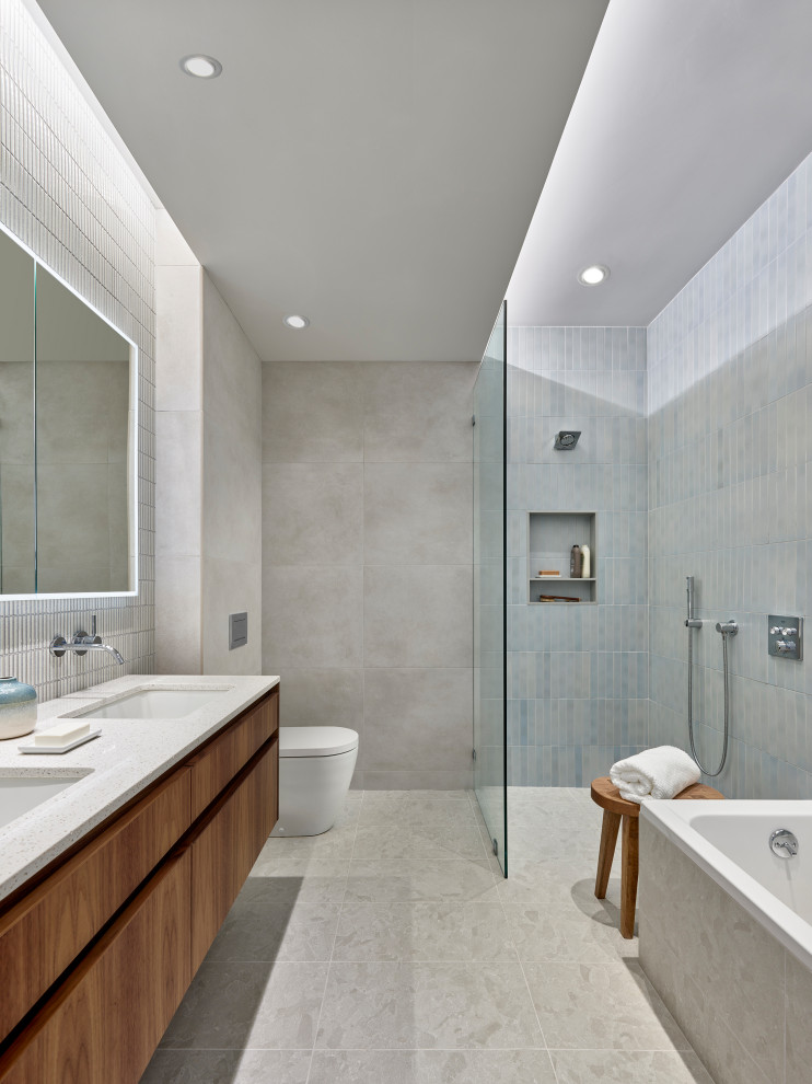 Contemporary master bathroom in Philadelphia with flat-panel cabinets, medium wood cabinets, an undermount sink, grey floor, an open shower, a niche, a double vanity, a floating vanity, porcelain tile, a corner tub, a curbless shower, a one-piece toilet, gray tile and white benchtops.