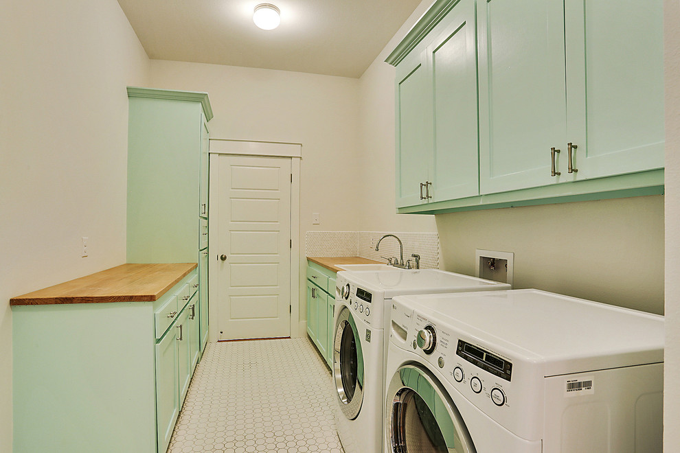 Inspiration for a large beach style galley utility room in New Orleans with shaker cabinets, wood benchtops, white walls, ceramic floors, a side-by-side washer and dryer, green cabinets and a drop-in sink.