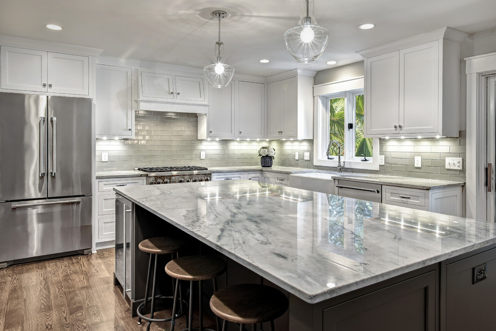 Inspiration for a large transitional u-shaped kitchen in Charleston with a farmhouse sink, shaker cabinets, white cabinets, marble benchtops, grey splashback, stainless steel appliances, dark hardwood floors, with island and brown floor.