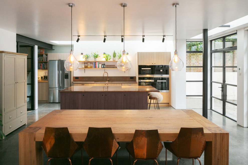 Große Moderne Wohnküche mit integriertem Waschbecken, hellen Holzschränken, Kupfer-Arbeitsplatte, Elektrogeräten mit Frontblende, Betonboden, Kücheninsel und grauem Boden in London