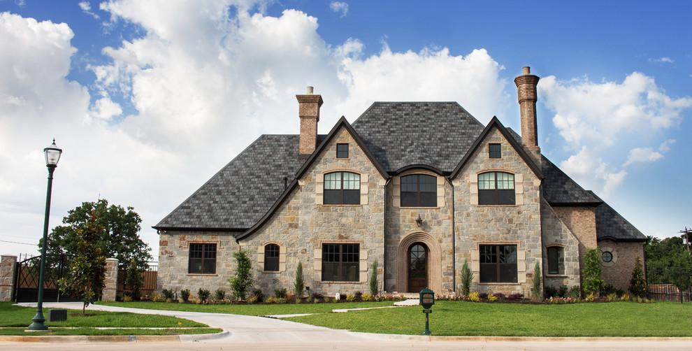 Design ideas for a large traditional two-storey beige house exterior in Dallas with stone veneer.