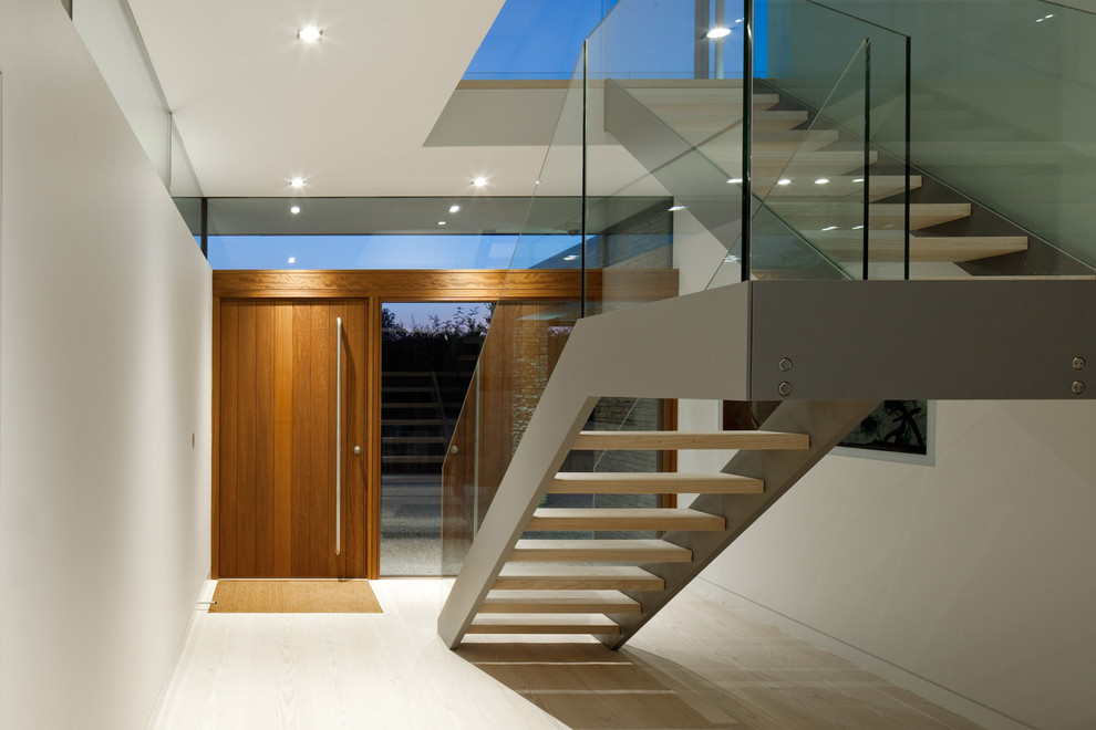 This is an example of a contemporary entryway in Hampshire with white walls, light hardwood floors, a pivot front door and a medium wood front door.